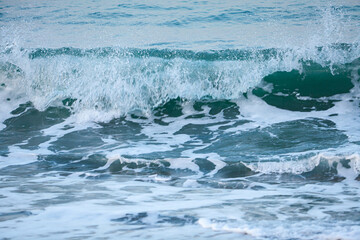 pebble stones on the sea beach, the rolling waves of the sea with foam