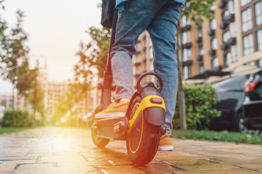 Low angle shot of the feet of unrecognizable man standing by electric kick scooter e-scooter outdoors