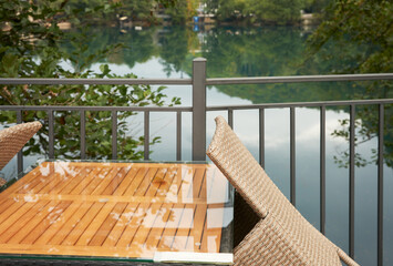 Vacation on the shore of a picturesque blue lake. The furniture of a summer cafe before opening in the morning. Surrounding nature in the background.