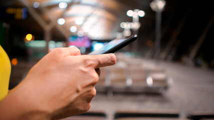 A closeup of woman hands using a smartphone in an airport terminal