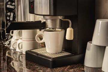 Coffee machine with a cup, on kitchen counter and blurred background.