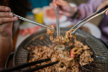 Gathered around a grill, friends are savoring and enjoying delicious, perfectly barbecued meat