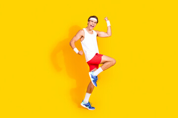 Energetic young man in sportswear expressing happiness against vibrant yellow background
