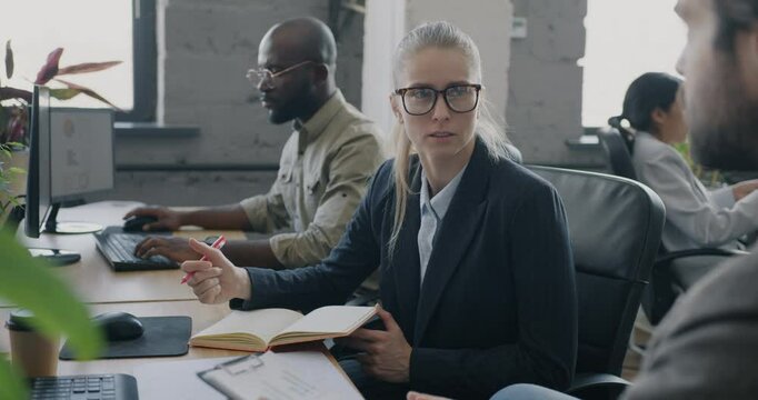 Business lady discussing corporate project with coworker writing ideas in notebook busy in office. Collaboration and businesspeople concept.