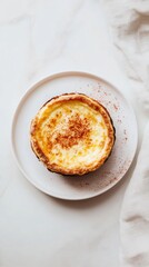 料理デザインのための、すっきりとしたミニマリストな背景の白い皿にのったおいしいカスタードタルト