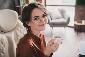 Photo of attractive young woman drink espresso wear brown satin shirt modern office room interior indoors workspace