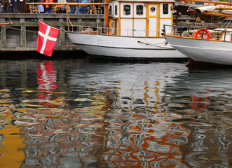 Danish boat and the red and white Danish flag reflecting in the water of the navigable canal in the...