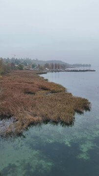Stunning drone footage capturing the tranquil beauty of a lake with crystal-clear water and a rocky shoreline surrounded by autumn foliage. Perfect for use in nature documentaries, travel content