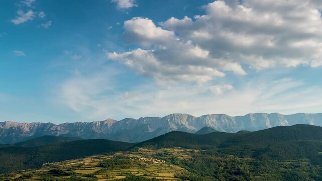 Landscape with fast movement of clouds in the sky, sunlight and shadows on the ground.Time Lapse. Zoom Out. View of the small village of Toloriu in the Pyrenees mountains of Catalonia, Spain.