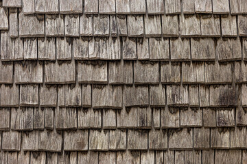 Old wooden tile roof. Pattern of a roof made of small wooden panels aged and marked by time and wear.