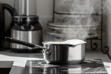 Boiling water with steam in a pot on an electric stove in the kitchen. 