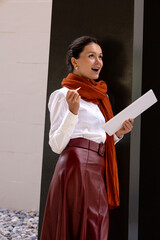 Business woman joyfully symbolizes success. He holds a white, clean tablet and a stylus pen. The...