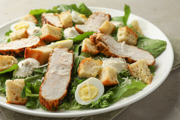 Tasty Caesar salad with chicken on light grey table, closeup