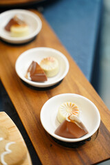 Close-up of gourmet chocolates in white ceramic plates arranged on a wooden tray. 