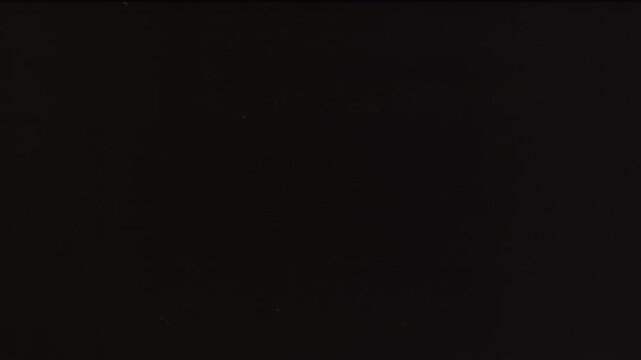 Subtle 8 mm film texture with noise and film dust on black background, perfect for screen mode overlays in retro-inspired cinematic editing, 4K