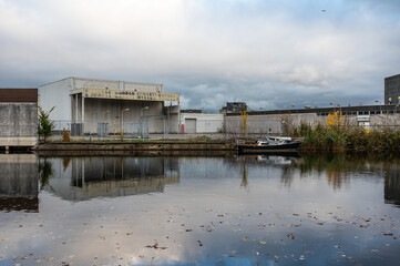 Fototapeta premium Houses, abandoned industry and boats reflecting in the Western market canal in Amsterdam, The Netherlands