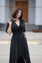 Portrait of a young beautiful dark-haired girl in an urban environment in summer.