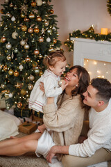 Family sitting near the Christmas tree and opening presents. Winter holidays.