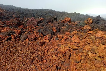 Field of aa lava rock, red and black volcanic clinkers in Piton de la fournaise, Reunion