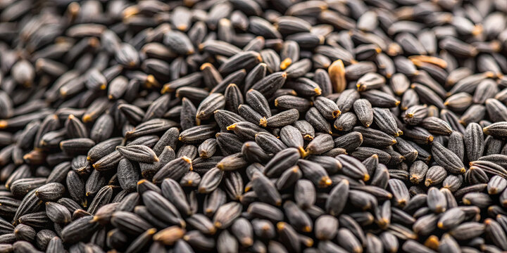 Close view of black cumin seeds spread out, highlighting their elongated shape and deep black color. The seeds are dry and create an interesting texture, appealing for culinary uses