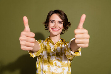 Confident young businesswoman showing thumbs up with a cheerful smile promoting a positive message...