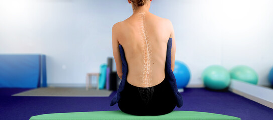 Young Woman from the back in a physiotherapy clinic, illustrating spinal scoliosis. Osteopathic medicine and physiotherapy. With blurred background of modern hospital or clinic