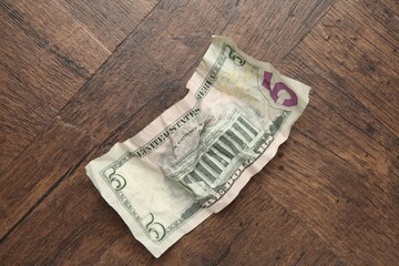 One crumpled dollar banknote on wooden table, top view