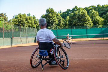 disabled tennis player in wheelchair playing a match on an outdoor clay court