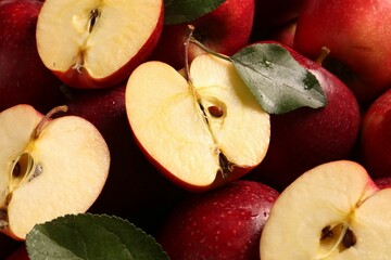 Fresh ripe red apples and green leaves as background, closeup