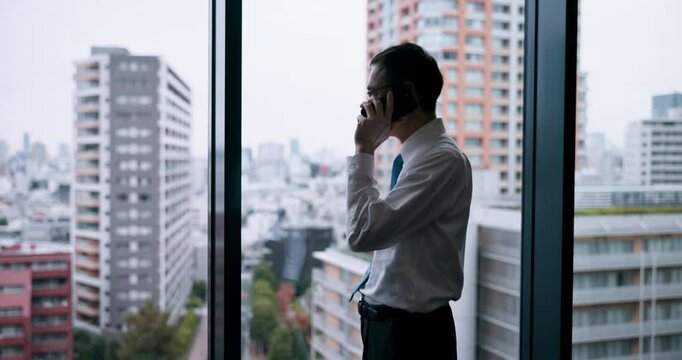 City, window and phone call in office, businessman and ideas for case, lawyer and consultation in law firm. Commitment, glass and planning for plea deal, legal and criminal defence attorney in Japan