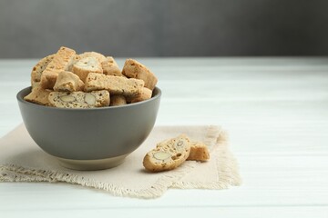 Traditional Italian almond biscuits (Cantucci) in bowl on white wooden table. Space for text