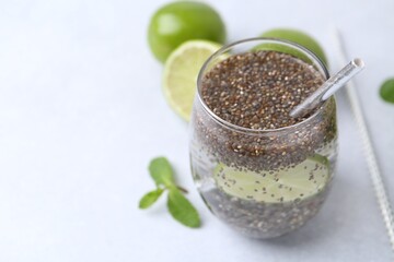 Glass of drink with chia seeds and lime on white table, closeup. Space for text