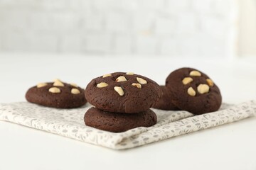 Tasty chocolate cookies with hazelnuts on white table, closeup