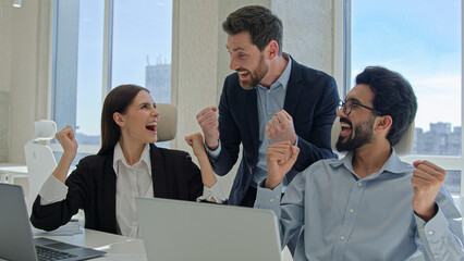 Happy creative team celebrate victory in office successful sales stock market data online business people businessmen and businesswoman winning teambuilding corporate teamwork with documents laptop