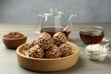 Tasty chocolate puffed rice balls served with tea on wooden table, closeup