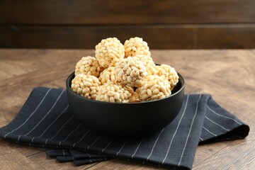 Tasty puffed rice balls in bowl on wooden table