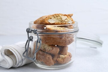 Traditional Italian almond biscuits (Cantucci) in jar on light table, closeup