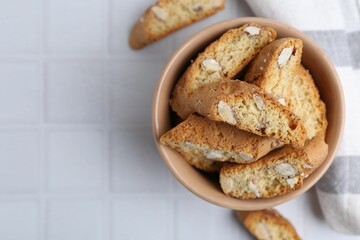 Tasty almond biscuits (Cantuccini) on white tiled table, flat lay. Space for text