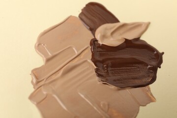 Samples of different foundations on beige background, closeup