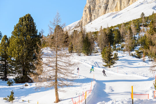 Group of skiers skking downhill on agroomed  ski slope on a clear winter day