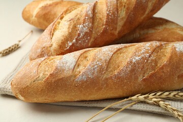 Fresh baguettes and spikes on beige table, closeup