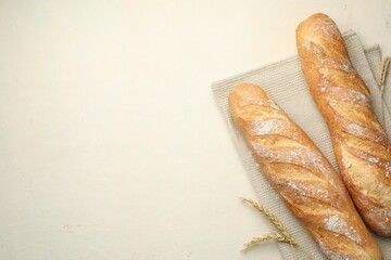 Fresh baguettes and spikes on beige table, flat lay. Space for text
