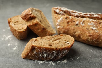 Cut fresh baguette on grey table, closeup