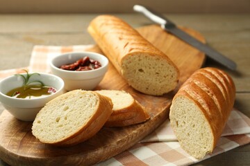 Cut fresh baguette served on wooden table, closeup