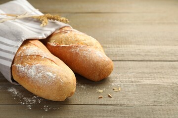 Freshly baked baguettes on wooden table, closeup. Space for text