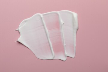 Cream on pink background, top view. Sample of cosmetic product