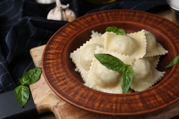 Delicious ravioli with cheese and basil served on wooden table, closeup
