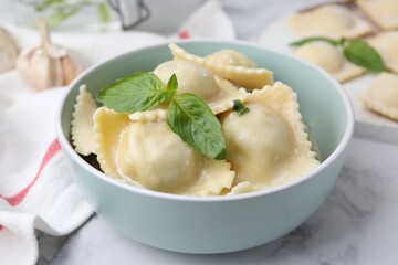 Delicious ravioli with cheese and basil served on white marble table, closeup
