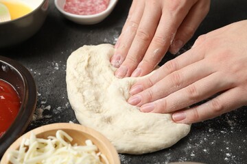Making calzone pizza. Woman with dough and ingredients at grey table, closeup
