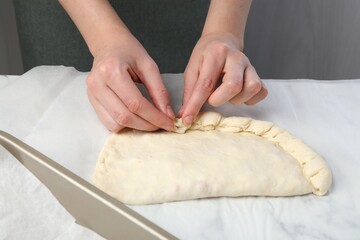 Woman making calzone pizza at table, closeup